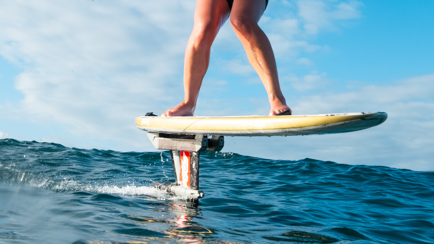 FoilBoost montado entre la tabla y el mástil, con el motor y la hélice bajo el agua