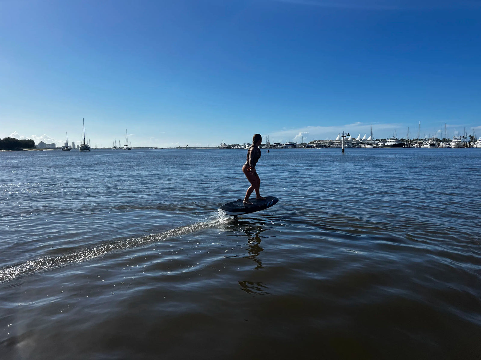 comparativa efoil vs hydrofoil de una persona montando un efoil en el agua con barcos al fondo