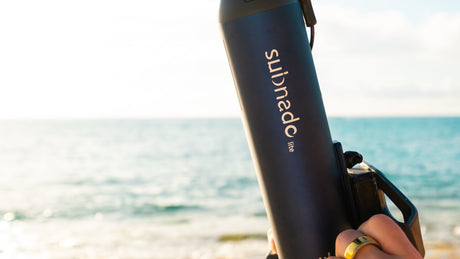 Subnado Lite sujeto con una mano frente al mar, con el soporte de empuñadura visible