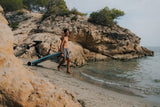 Hombre cargando una tabla Flyer EVO por una playa rocosa