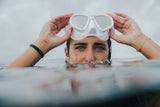 Primer plano de una mujer con máscara de buceo levantada, sonriendo