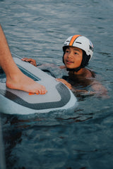 Adolescente tumbado sobre la tabla del Flyer EVO sonriendo, con casco puesto